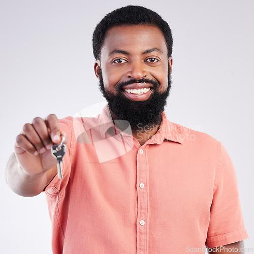 Image of Real estate, happy and portrait of a black man with keys isolated on a white background in a studio. Smile, pride and African guy showing a key to a new home, house or apartment as a property owner