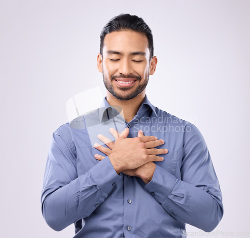 Image of Pray, hands on chest and happy man in studio with self love, hope and love on grey background. Praying, hand and open heart gesture by male show emoji, gratitude and calm zen while standing isolated