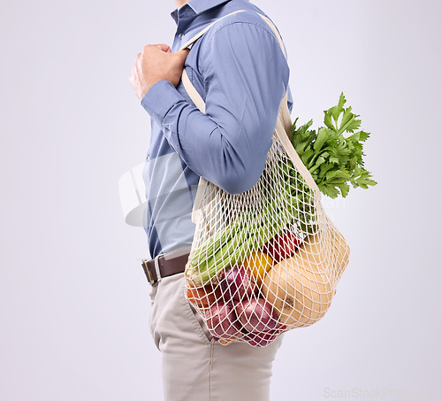 Image of Diet, groceries and man with vegetables in studio for a healthy, vegan and wellness lifestyle. Health, nutrition and closeup of male model with bag of crops or food to cook dinner by gray background.