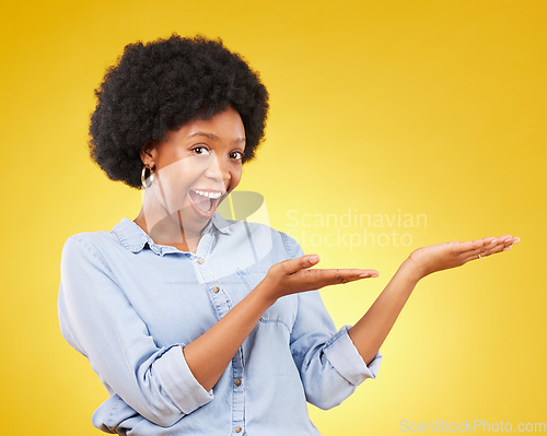 Image of Space, portrait of a black woman in studio showing mockup for advertising or marketing. Happy, smile and face of African female model pointing to mock up for product placement by yellow background.