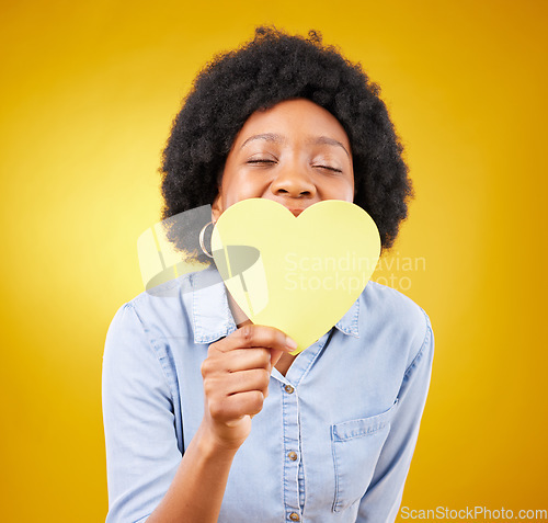 Image of Paper, heart and happy with black woman in studio for romance, positive and emotion. Happiness, love shape and giving with female isolated on yellow background for date, feelings and affectionate