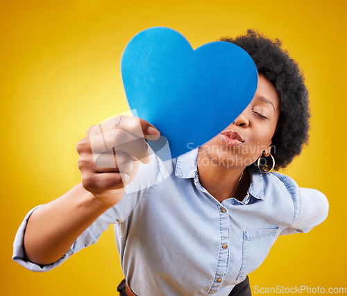 Image of Paper, heart and kissing with black woman in studio for romance, positive and emotion. Happiness, love shape and giving with female isolated on yellow background for date, feelings and affectionate