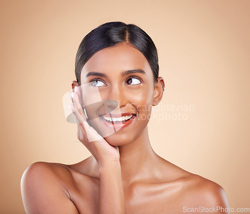 Image of Thinking face, smile or makeup on happy woman in studio isolated on beige background for natural facial skincare. Hand, beauty or beautiful young Indian girl with luxury self care or glowing results