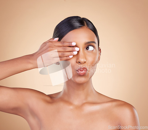 Image of Indian woman, studio and beauty with hand on eye for funny face, pouting and cosmetics by background. Gen z model girl, young asian and makeup for cosmetic wellness, natural skin glow or aesthetic