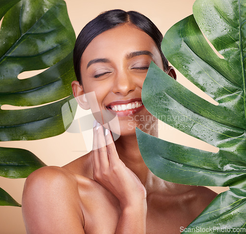 Image of Woman, face and smile with leaf for natural skincare cosmetics, self love and care against studio background. Happy female beauty holding leafy green organic plant in sustainable eco facial treatment