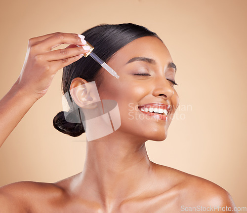 Image of Happy woman, dropper and retinol on face for beauty, skincare or cosmetics against studio background. Female model with smile applying oil drop to skin for hydration, moisturizer or facial treatment