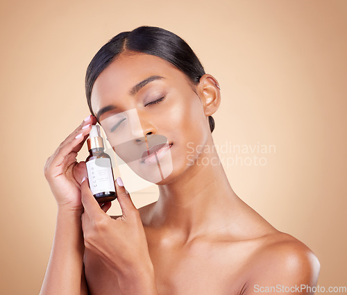 Image of Face serum, eyes closed or model woman in studio on beige background for skincare headshot. Facial, natural beauty or young Indian girl relaxing with essential oils or glowing luxury self care makeup