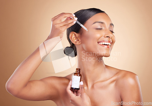 Image of Woman, dropper and retinol on face for skincare beauty or cosmetics against a studio background. Happy beautiful female model applying oil drop to skin for hydration, moisturizer or facial treatment