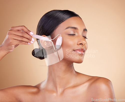 Image of Woman, roller and face for skincare beauty, cosmetics or dermatology and anti aging against a studio background. Happy female model rolling skin for facial treatment, natural health and wellness