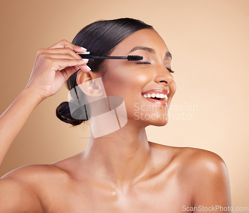 Image of Makeup, happy and woman with mascara for eyelashes isolated on a studio background. Smile, cosmetology and Indian girl with a brush for applying cosmetics, pomade product or treatment to lashes