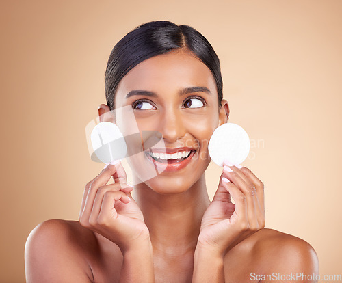 Image of Smile, happy or woman with cotton pad in studio isolated on beige background for facial skincare. Face headshot, natural beauty or beautiful young Indian girl with luxury self care or glowing results