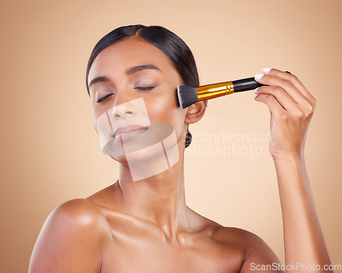 Image of Woman, brush or makeup artist with beauty, cosmetic products or self care in studio background. Eyes closed, model face or relaxed young Indian girl with cosmetics, glowing skincare or application