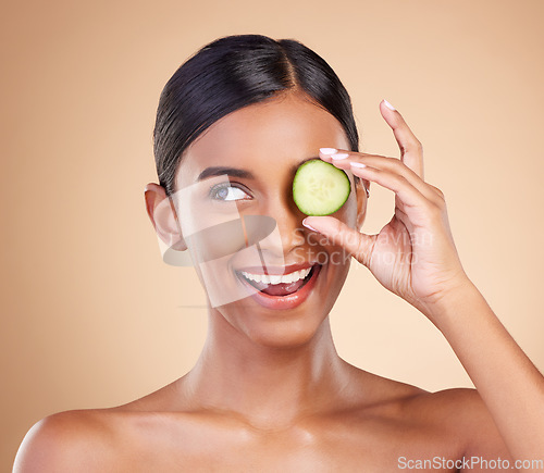 Image of Smile, beauty or happy woman with cucumber for cleaning, detox and healthy facial treatment routine. Wellness, face or Indian girl with skincare nutrition or cosmetics isolated on studio background