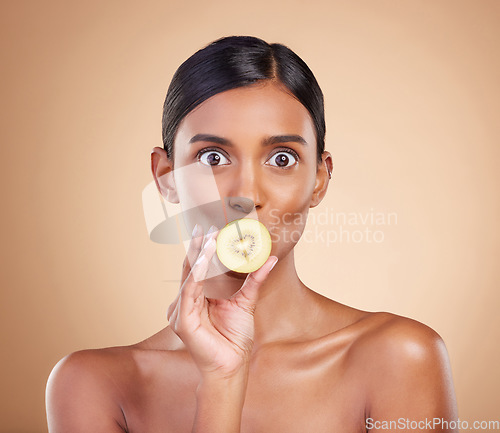 Image of Wow, beauty or woman with kiwi for healthy detox, skincare or facial treatment routine in headshot. Food nutrition, face or crazy Indian girl with wellness or fruits isolated on studio background