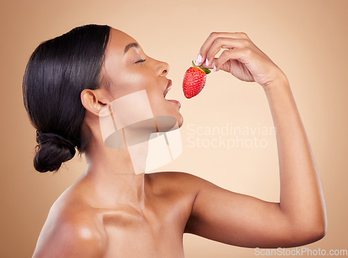 Image of Woman, strawberry and eating for natural skincare, beauty and nutrition cosmetics against a studio background. Female nutritionist holding fruit to eat for healthy organic diet, meal or wellness