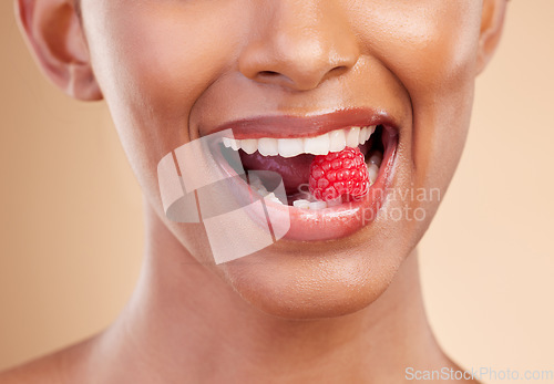 Image of Woman, mouth and raspberry for skincare nutrition, dermatology or diet health plan against a studio background. Female lips with fruit for natural organic food, self care or eat for healthy wellness