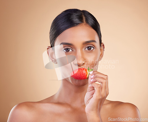 Image of Eating strawberry, portrait or healthy Indian woman with skincare beauty or wellness in headshot. Food nutrition, face or young girl model with vitamin c or red fruits isolated on studio background