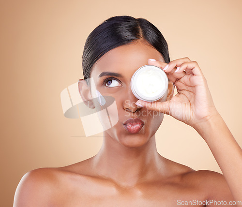 Image of Face, skincare or Indian woman with cream for beauty or wellness isolated on studio background. Cosmetics or girl model with facial self care or dermatology product for anti aging or dark circles