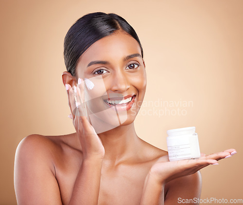 Image of Portrait, product and lotion with a woman in studio on a beige background for beauty or skincare. Face, advertising and moisturizer with an attractive young female model holding a cosmetics container