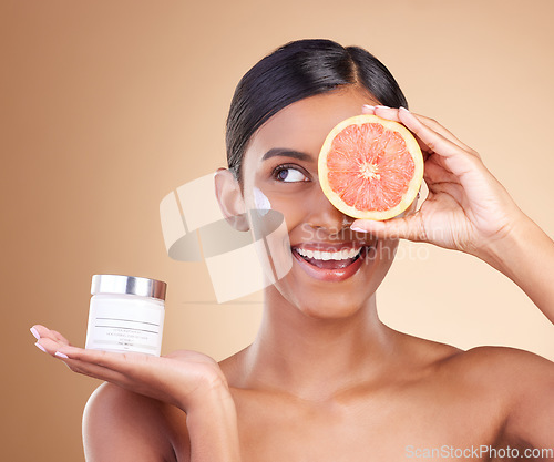 Image of Grapefruit, skincare or happy woman with cream product for beauty or young face isolated on studio background. Cosmetics, smile or Indian girl with facial moisturizer or dermatology lotion for glow