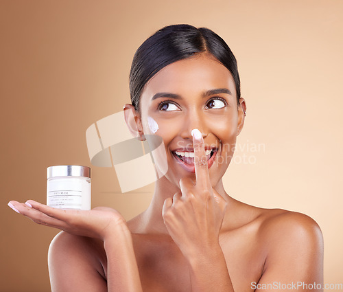 Image of Woman, face and applying moisturizer cream for beauty skincare cosmetics, self love or care against a studio background. Happy female with smile for lotion, moisturizing creme or facial treatment