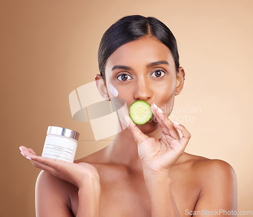 Image of Woman, moisturizer cream and cucumber for natural skincare, beauty and nutrition against studio background. Portrait of female holding vegetable, creme or lotion for healthy organic diet or wellness