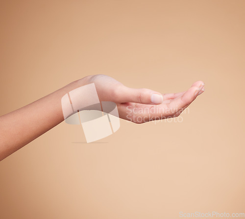 Image of Hands, palm and product placement for mockup in studio isolated on a brown background. Skincare, dermatology and woman model with hand out for marketing, advertising or branding space for mock up.