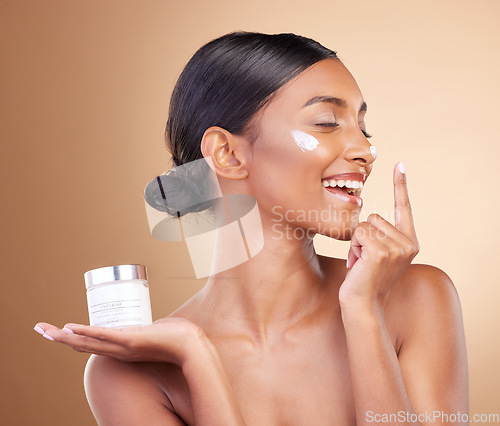 Image of Woman, face and smile with moisturizer cream for beauty skincare cosmetics, self love or care against a studio background. Happy female smiling for lotion, moisturizing creme or facial treatment