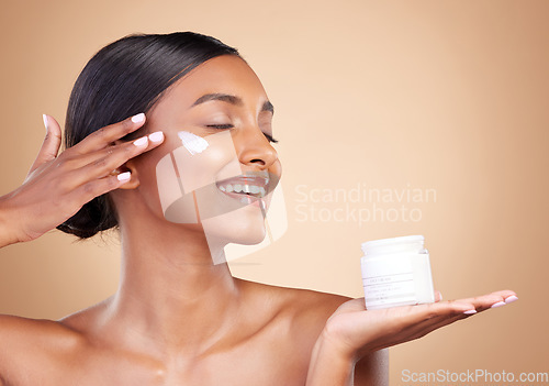 Image of Smile, skincare or happy woman with cream product for beauty or young face isolated on studio background. Body cosmetics, youth or Indian girl with facial moisturizer or dermatology lotion for glow
