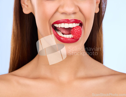 Image of Beauty, health and raspberry with mouth of woman in studio for nutrition, diet or detox. Cosmetics, natural and self care with girl model eating fruit on blue background for wellness, organic or glow