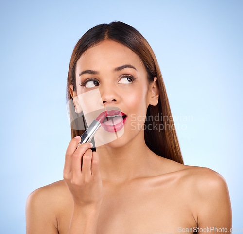 Image of Beauty, woman thinking and red lipstick or makeup on face for cosmetics product in studio. Aesthetic female model on a blue background think of idea for facial glow and color application for lips