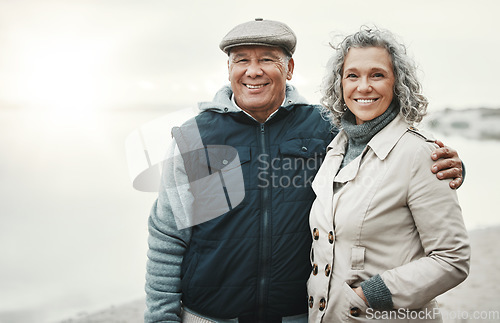 Image of Portrait, winter and senior couple hug, beach for holiday or anniversary getaway with joy, smile or retirement. Face, old woman or mature man embrace, happiness or loving together for romance or love