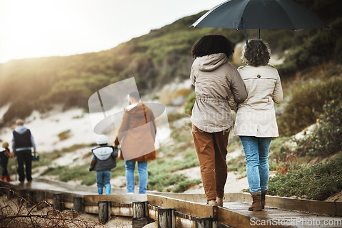 Image of Back, nature and a family walking on a wooden path outdoor together for holiday or vacation. Love, environment and bonding with relatives taking a walk near the beach while bonding in winter