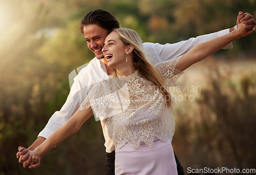 Image of Happy, love and couple laugh in nature at sunset for romance, bonding and quality time together. Summer, dating and man and woman holding hands on holiday, honeymoon vacation and relax on weekend