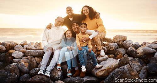Image of Happy family, parents and children in beach portrait with excited face, sitting or relax with grandparents on rocks. Woman, man and kids by ocean for love, care and bonding on holiday by sunset sky