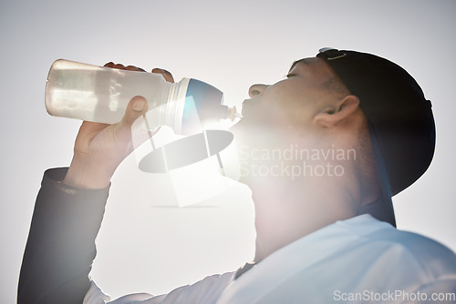 Image of Baseball player, drinking water or thirsty sports man on field in training match or game in a stadium. Sunshine, cardio fitness workout or healthy softball athlete drinks liquid for energy in summer