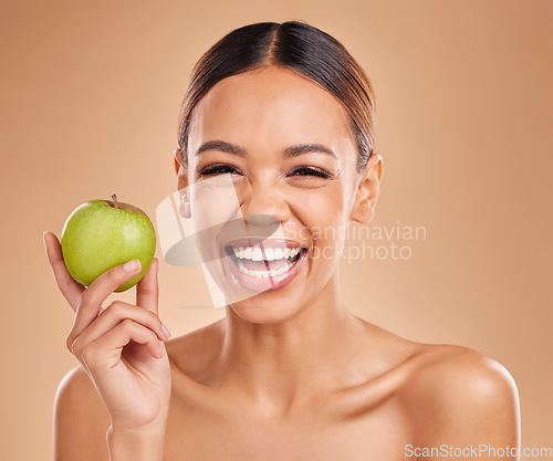 Image of Portrait, beauty and woman with skincare, apple and smile with girl against brown studio background. Portrait, female and lady with fruit, diet and cosmetics with happiness, healthy lifestyle or joy