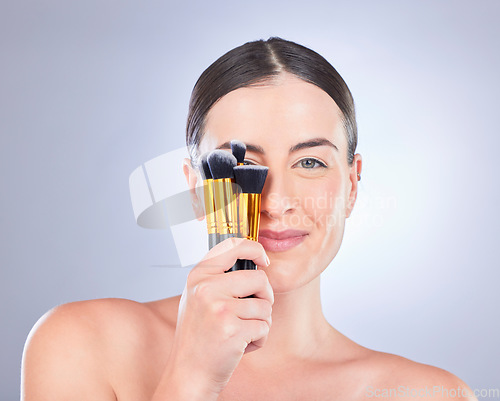 Image of Makeup, cosmetic and portrait of a woman with brushes isolated on a studio background. Happy, beauty and model showing a brush set for cosmetics, foundation application and glamour on a backdrop