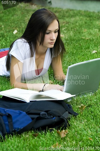 Image of Cute teen girl laying down on the grass studying