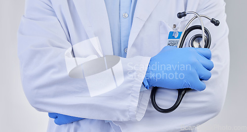 Image of Arms crossed, closeup doctor and stethoscope in studio for medicine, medical services and wellness consulting. Healthcare worker, zoom and professional cardiology on background for heart consultation