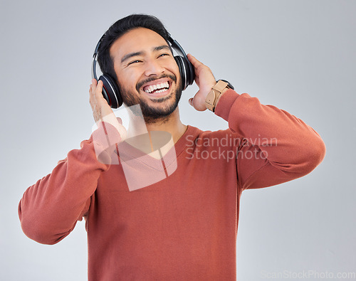 Image of Happy asian man, headphones and music in studio with streaming, audio or web subscription by background. Student guy, listening and laughing with comic podcast, standup comedy album or hip hop single