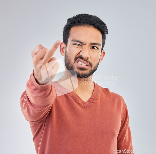 Image of Rude, middle finger and portrait of asian man in studio for fail, conflict and problem. Annoyed, upset and aggressive with male and hand gesture on gray background for hate, disrespect and furious