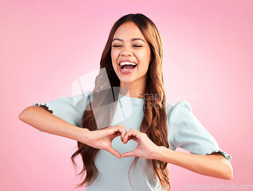 Image of Laugh, heart hands and happy with woman in studio for romance, positive and kindness. Love, support and emoji with female and shape isolated on pink background for emotion, hope and gesture