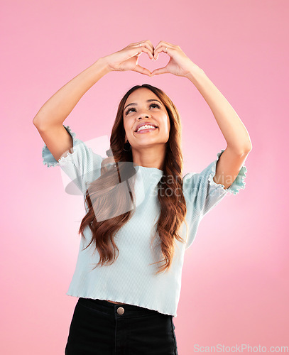 Image of Happy, heart hands and shape with woman in studio for romance, positive and kindness. Love, support and emoji with female and smile isolated on pink background for emotion, hope and gesture