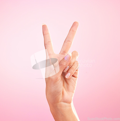 Image of Woman, hands and peace sign, emoji or symbol for freedom against a pink studio background. Hand of female showing peaceful V icon or shape for hope, support or trust in vote or voice on mockup