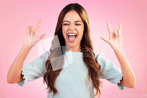 Image of Portrait of woman, rock hand gesture and excited expression in studio, smile on face and pink background. Crazy, wild hispanic model and hands in devil sign or emoji with happy punk attitude symbol.