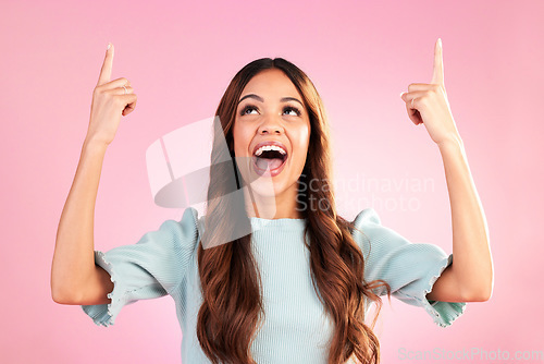 Image of Excited, pointing mockup and woman on pink background with happy, smile and space for sale, deal or discount. Advertising, hands and girl looking up for product placement, promotion and announcement