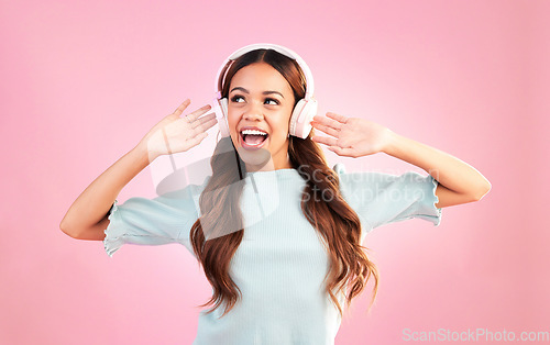 Image of Music headphones, singing and woman dancing in studio isolated on a pink background. Singer, radio dance and happy mixed race female streaming, enjoying and listening to audio, sound track or podcast