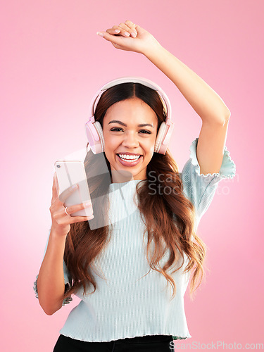 Image of Music headphones, phone and portrait of woman in studio isolated on a pink background. Smile, radio dance and happy female with mobile streaming, enjoying and listening to audio, sound or podcast.