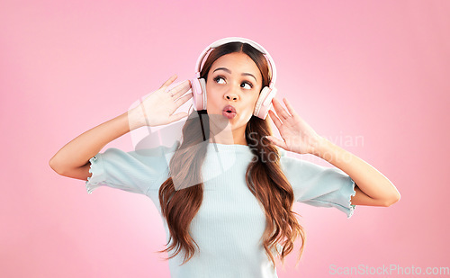 Image of Music headphones, singing and woman whistle in studio isolated on a pink background. Singer, thinking and mixed race female streaming, enjoying and listening to audio, sound track or radio podcast.